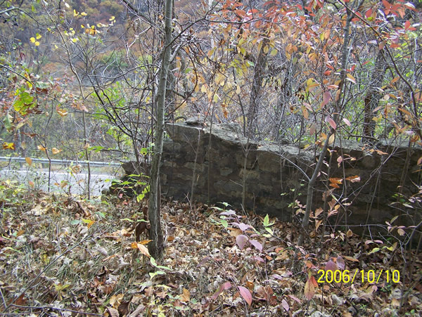 A last view of the end of the old retaining wall, with the modern highway visible in the background.