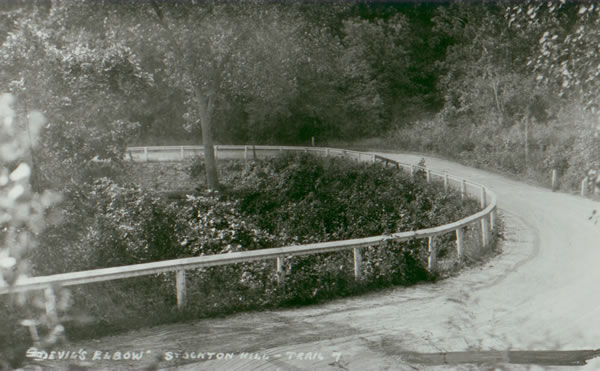A postcard showing the "Devil's Elbow" as it appeared between 1921 and 1932. Note the wood guard rails, and the stone retaining wall. 